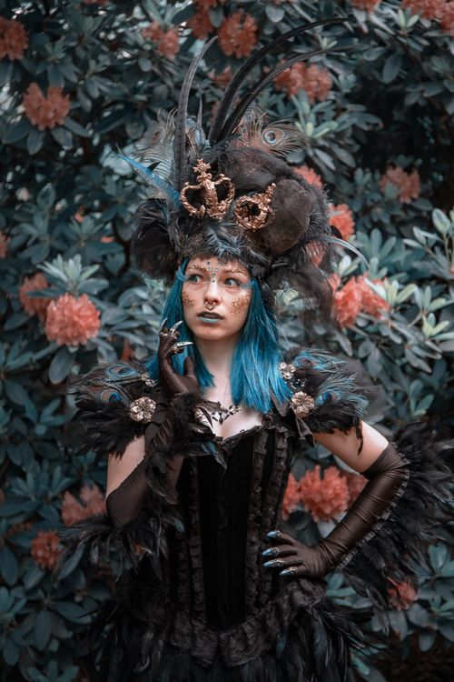 Free A woman in elaborate fantasy costume poses in a garden setting, combining elements of fashion and art. Stock Photo