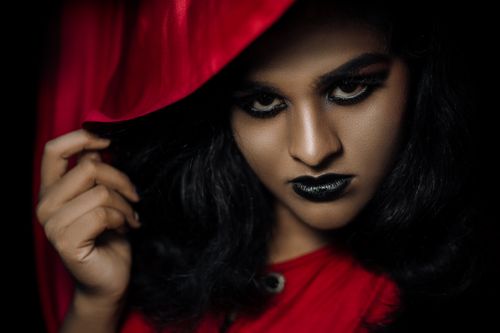 Free Intense portrait featuring bold makeup and red hood for a dramatic effect. Stock Photo