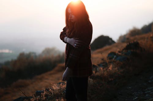 Young Woman in Shirt Posing on Hillside at Dusk