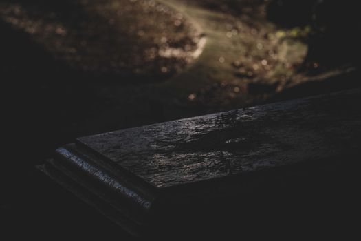 High angle of aged shabby gravestone placed near narrow alley in cemetery at autumn night