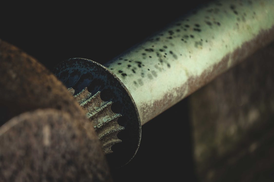 Closeup of old weathered rusty pipe of metal mechanism in industrial workshop against blurred background
