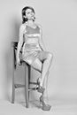Stylish female sitting on wooden chair in light studio