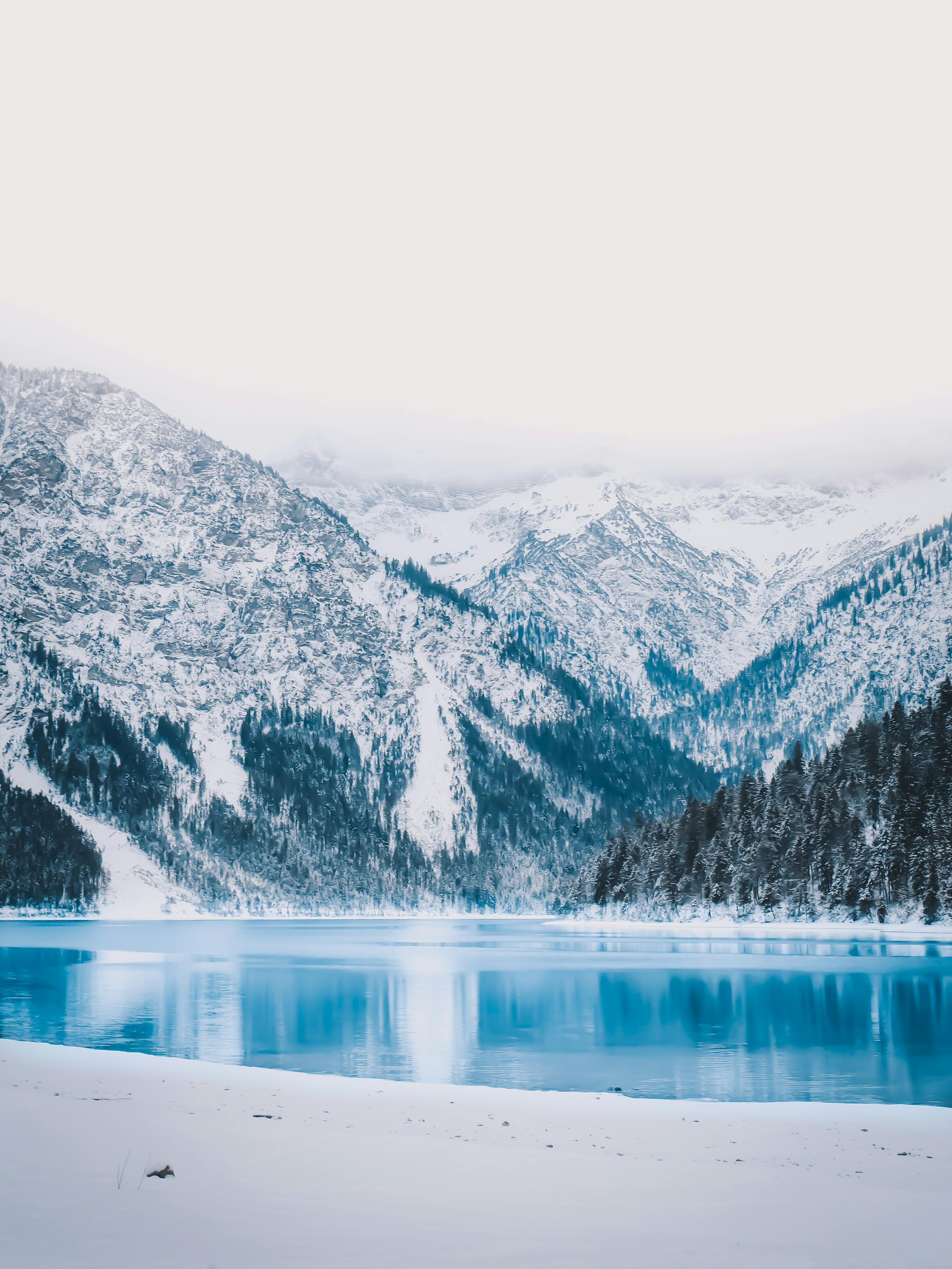 A beautiful snowy landscape of Tyrol mountains and blue lake in Austria
