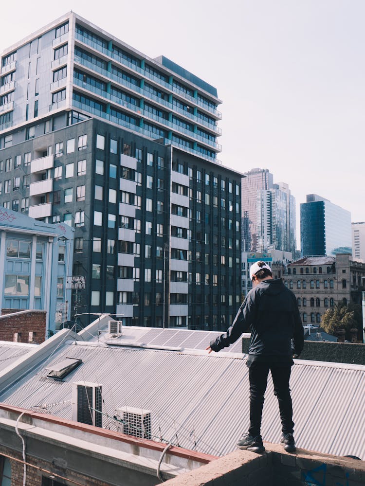 A Man Standing On The Rooftop Edge