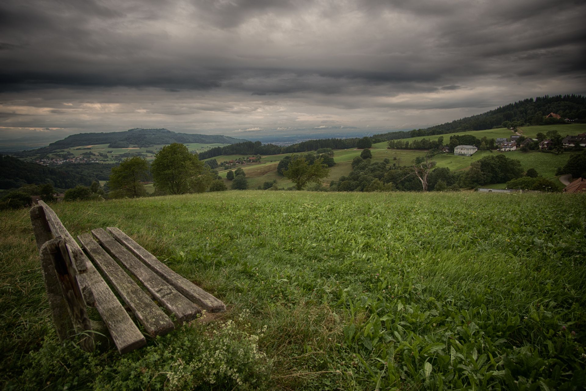 Gloomy countryside landscape with bench and rolling hills in Horben, Germany. Serene nature view.