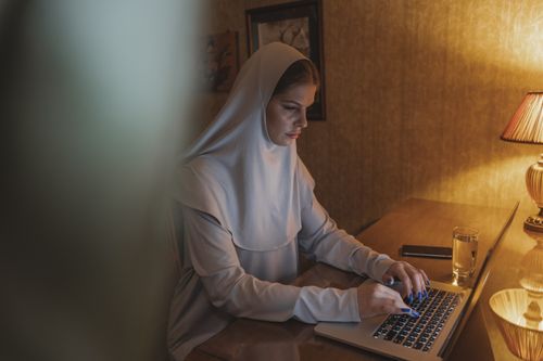 Free A woman in hijab focused on her laptop in a cozy home office setting. Stock Photo