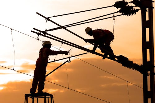 Silhouette of Two Electricians Working