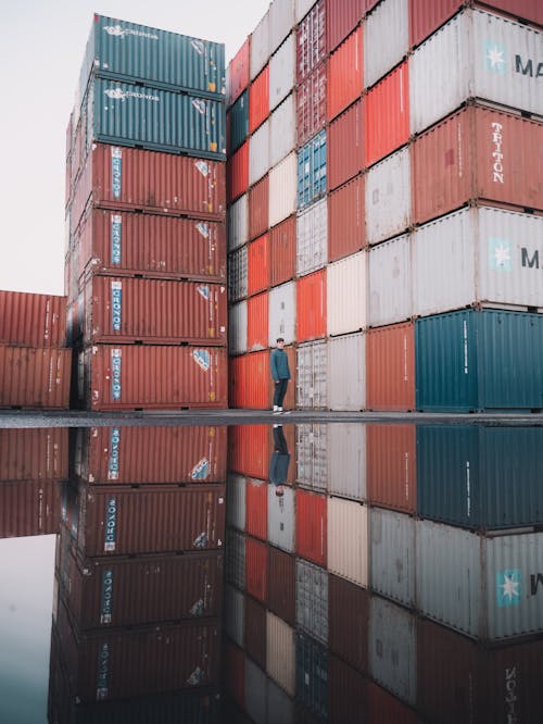 Free Man Standing Near A Stack Of Cargo Containers Stock Photo