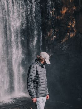 一名身穿灰色夹克、头戴帽子的男子站在澳大利亚维多利亚州的特伦瑟姆瀑布附近