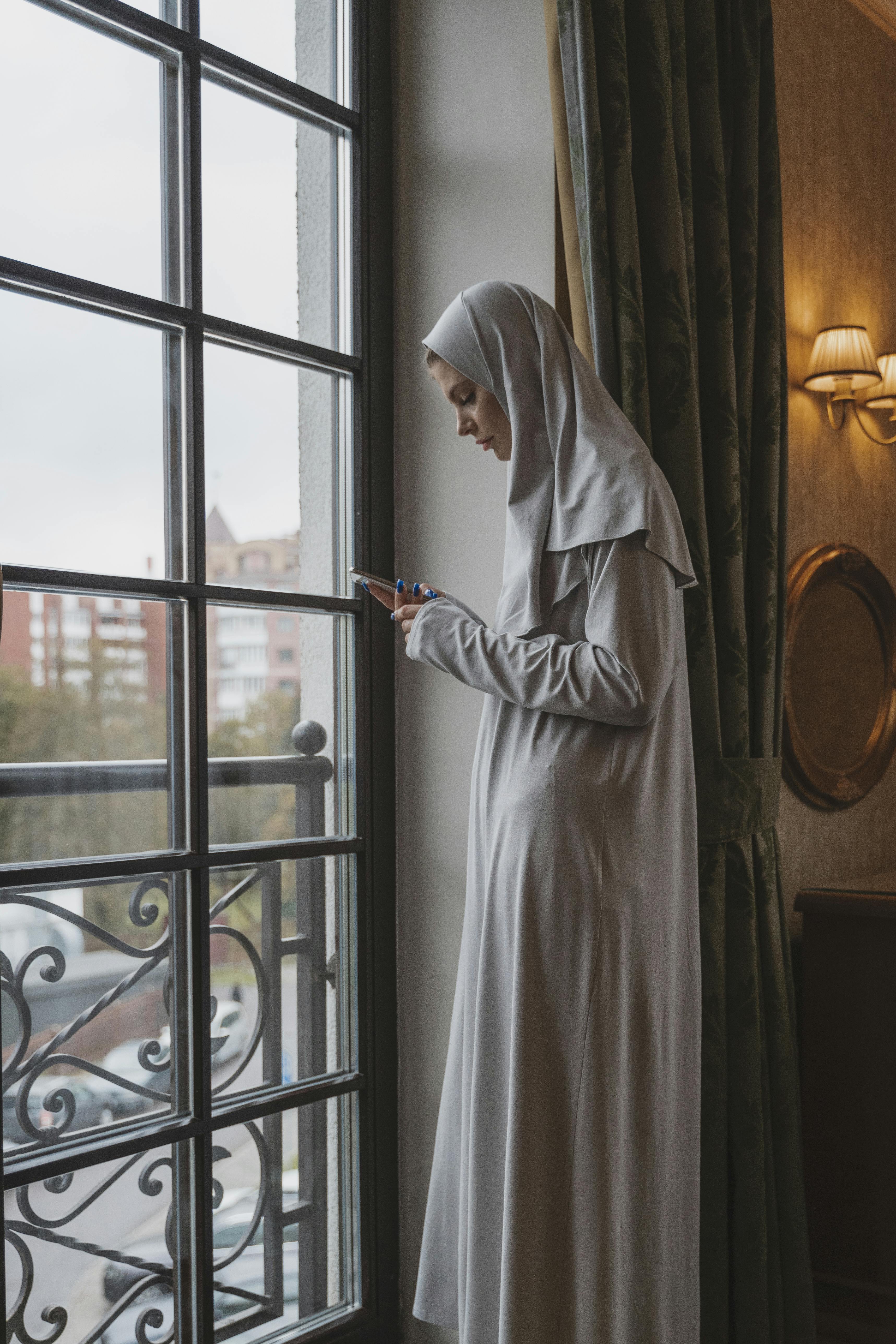 woman in white hijab standing near window