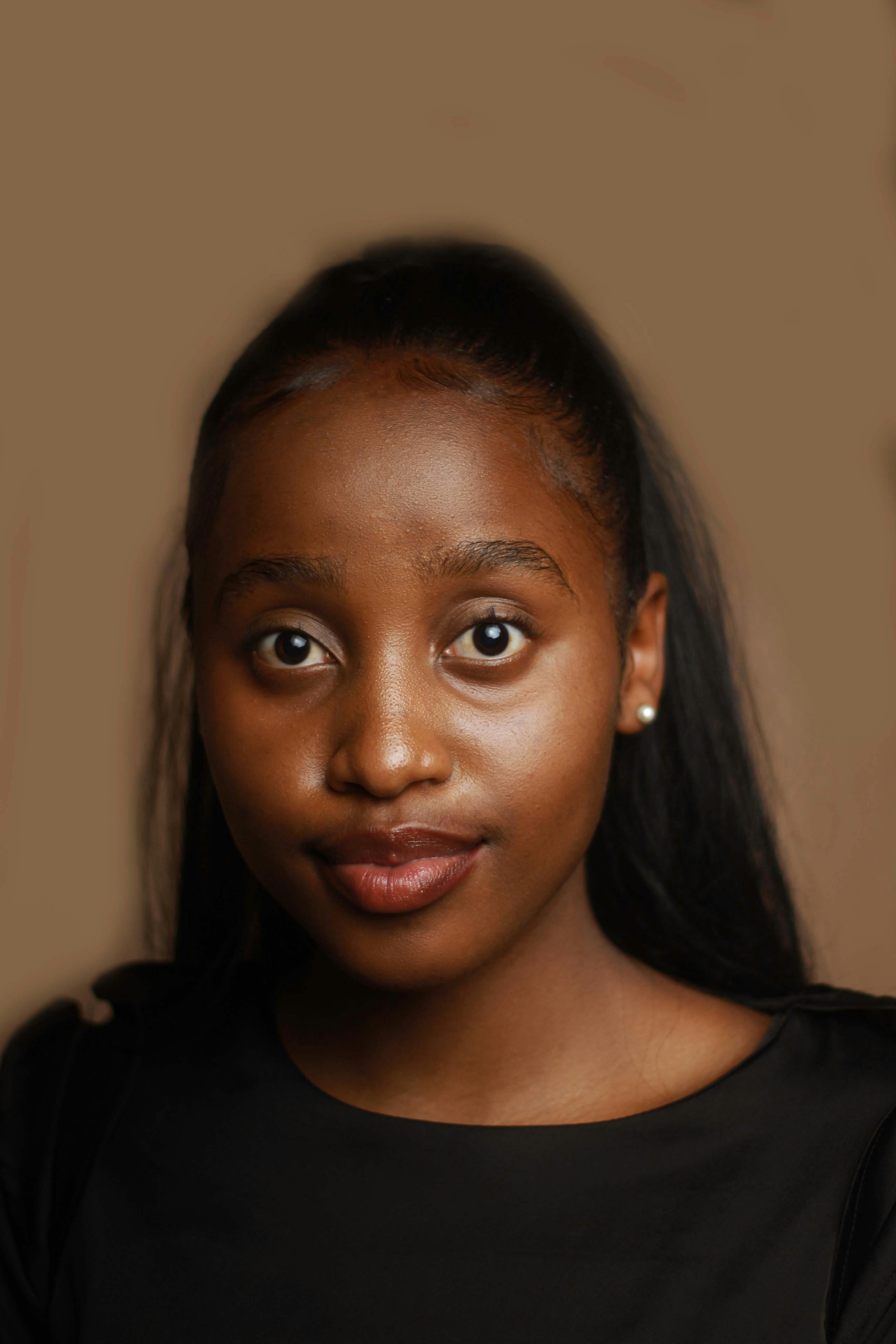 young black lady looking at camera in brown studio