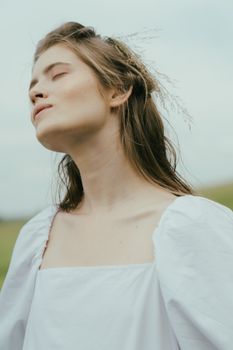 一位身着白色衬衫的女子安静地闭着眼睛，在户外拥抱自然