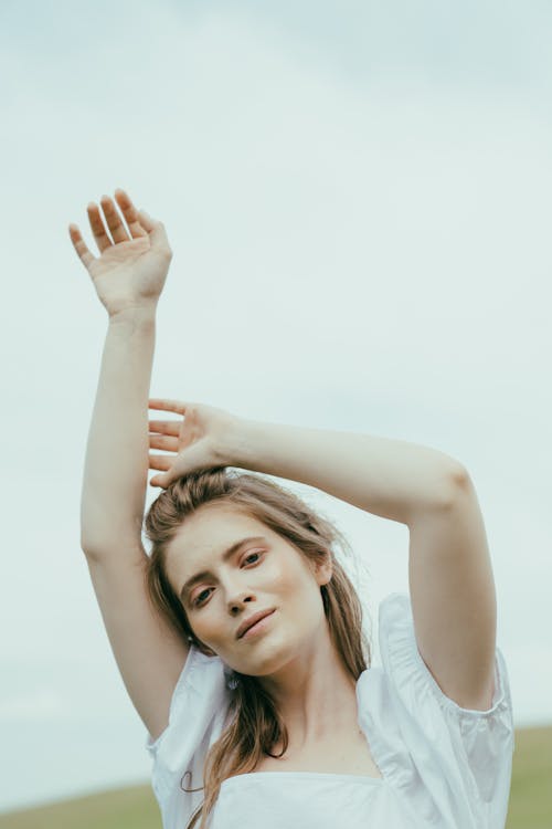 A Woman Smiling and Raising her Hands while Posing