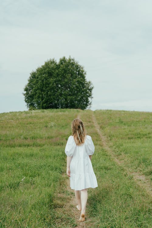 A Person Walking Barefeet on Green Grass Field