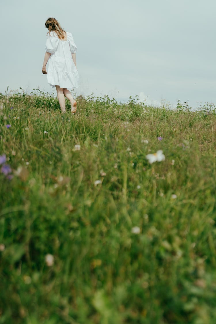 A Woman Walking Barefeet On The Grass Field