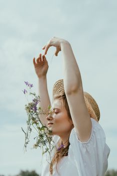一位身穿白色连衣裙、头戴草帽的女子正在户外享受大自然