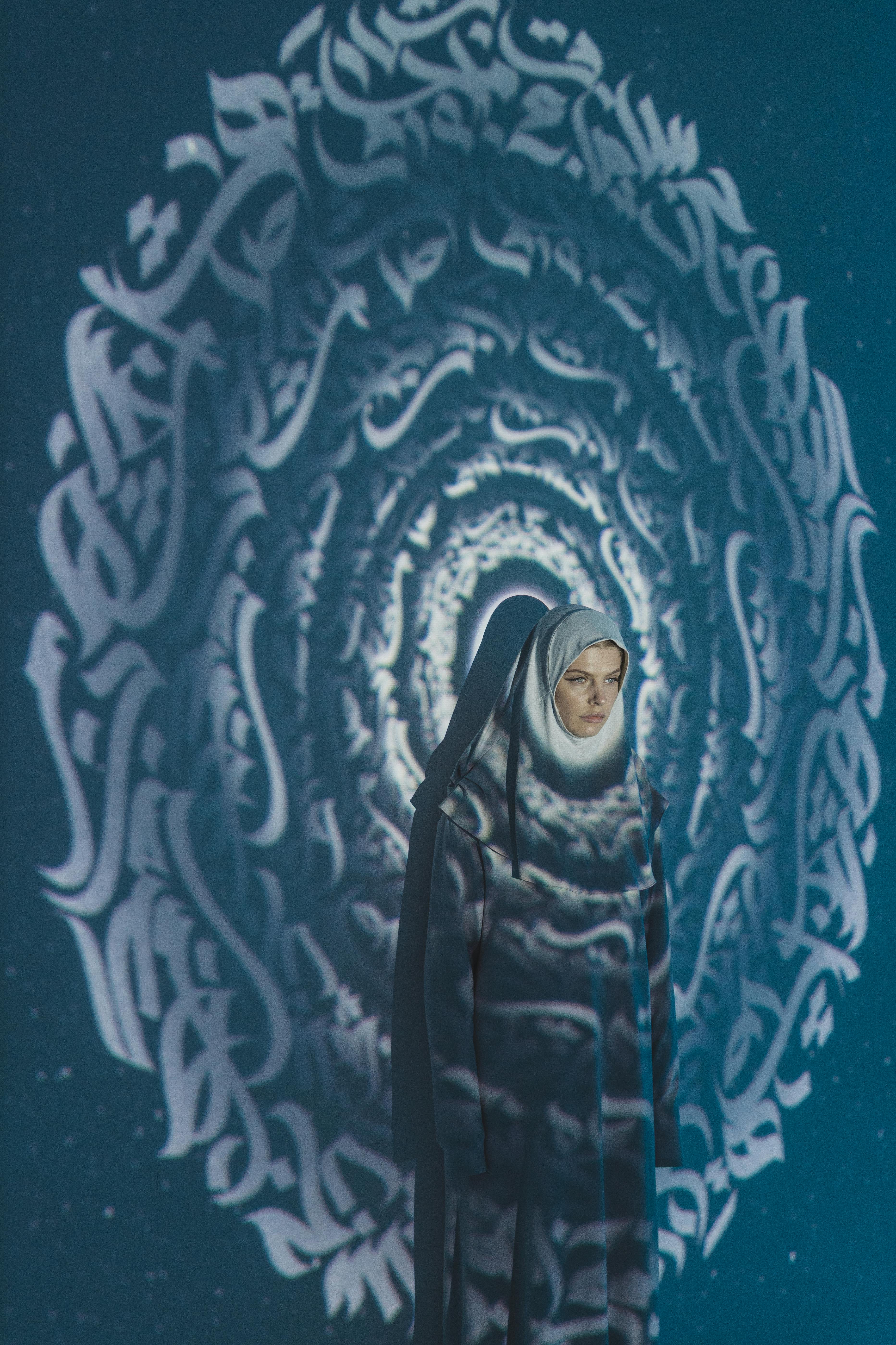 Portrait of a woman in traditional hijab with artistic calligraphy background.