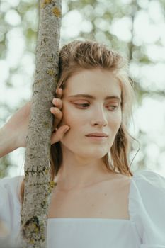 一位女人在宁静的户外环境中，深思熟虑地靠在树干上的肖像