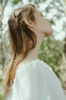 一名女子闭着眼睛，在绿植环绕中享受大自然的侧影