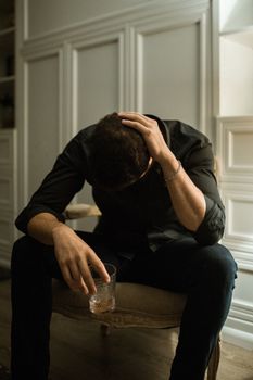 一名陷入困境的男子坐在室内，手拿饮料，显得孤独