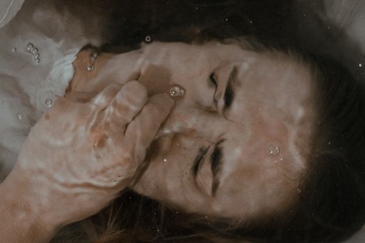 Woman holding nose under water