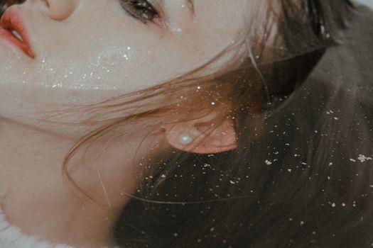 Crop sensual female with smeared makeup lying in bathtub with hair flowing in water having depression