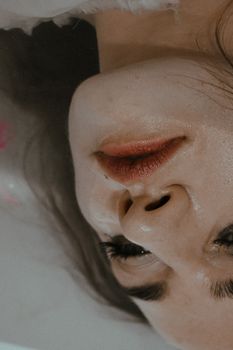 从上面看，温柔无情的女性正涂抹着化妆品躺在浴缸的水中