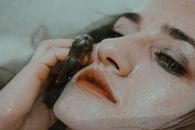 一位温柔忧郁的女人在浴缸里化妆，特写镜头中她正触摸自己湿漉漉的脸