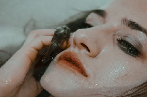 Free Closeup of tender melancholic woman with makeup smeared touching wet face in tub of water Stock Photo