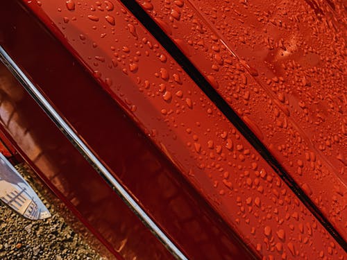 Abstract background of shiny red vintage car with chrome details covered with rain drops