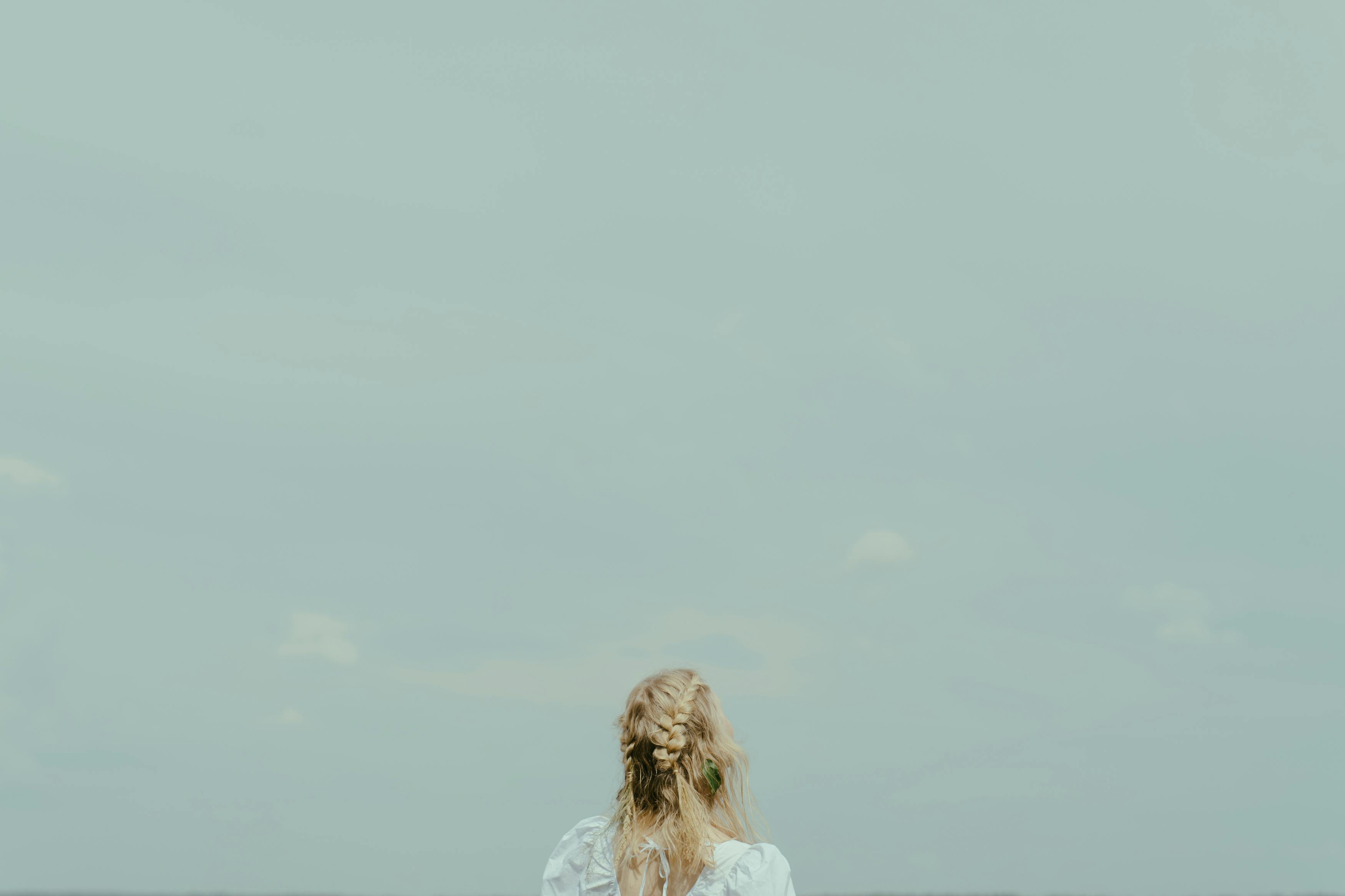 一名金发女子站在户外，凝望着广阔的蓝天，尽显自由与宁静