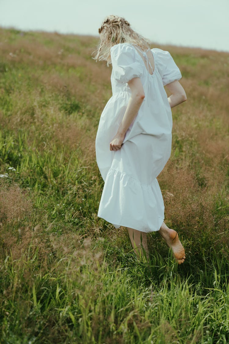 A Woman Walking Barefoot On The Grass 