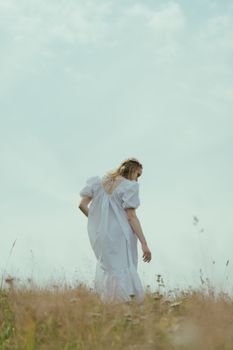 一位身穿白色连衣裙的女子走过宁静的草地，展现了乡村的宁静