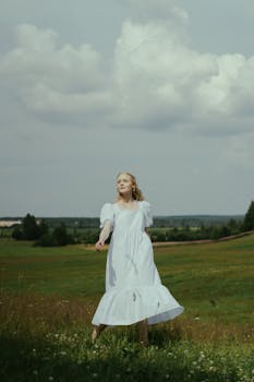 广阔的绿色草地上，一个穿着白裙子的女人正享受着平静的宁静时刻