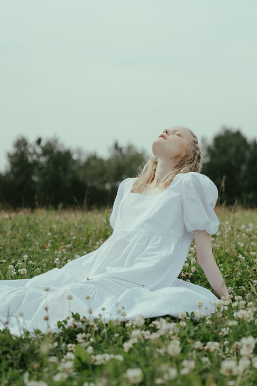 Girl in White Dress Sitting on Green Grass Field