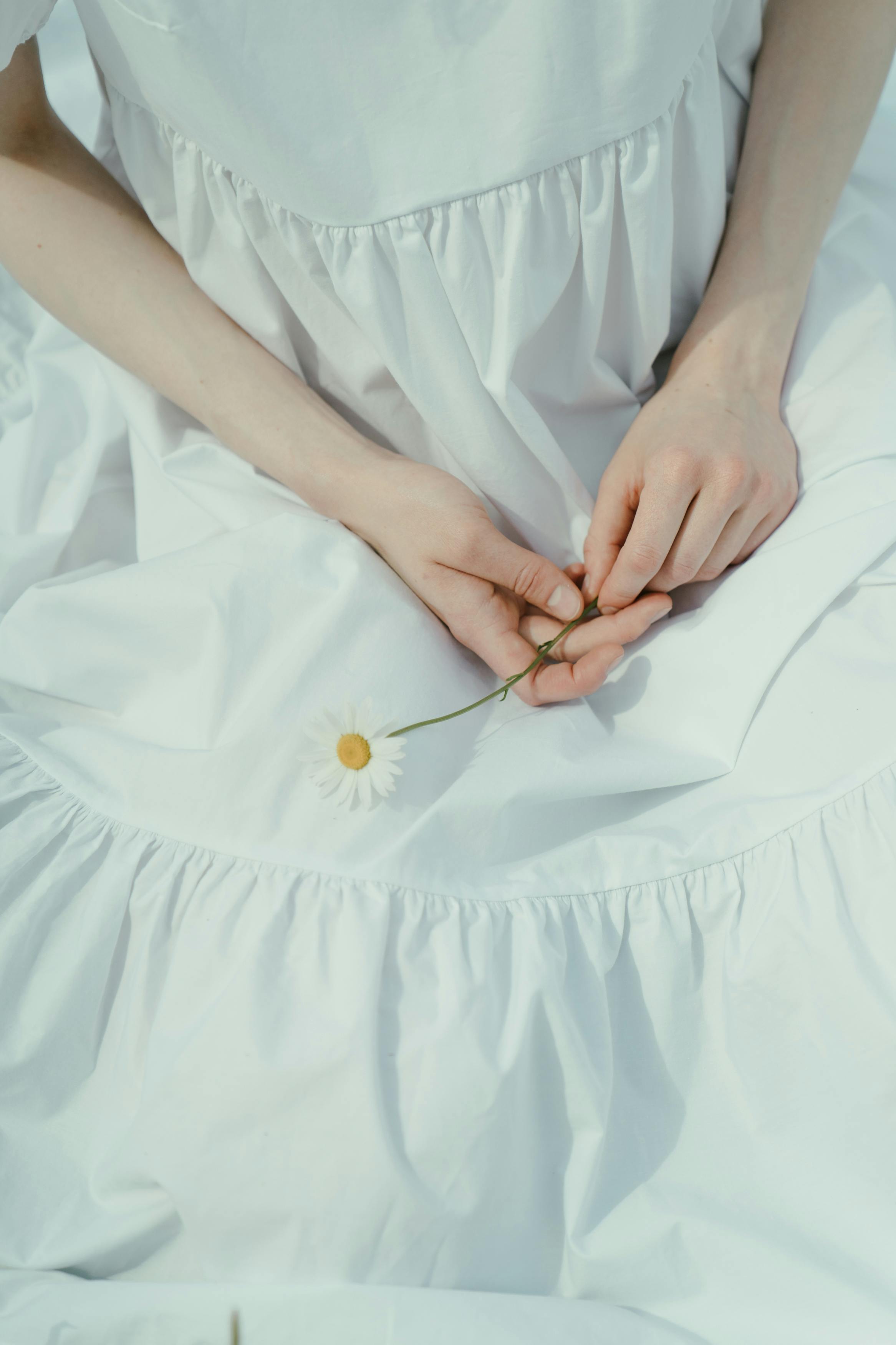 这幅优雅的肖像描绘了一位身着白色连衣裙的女子，她正轻轻拿着一朵洋地黄花