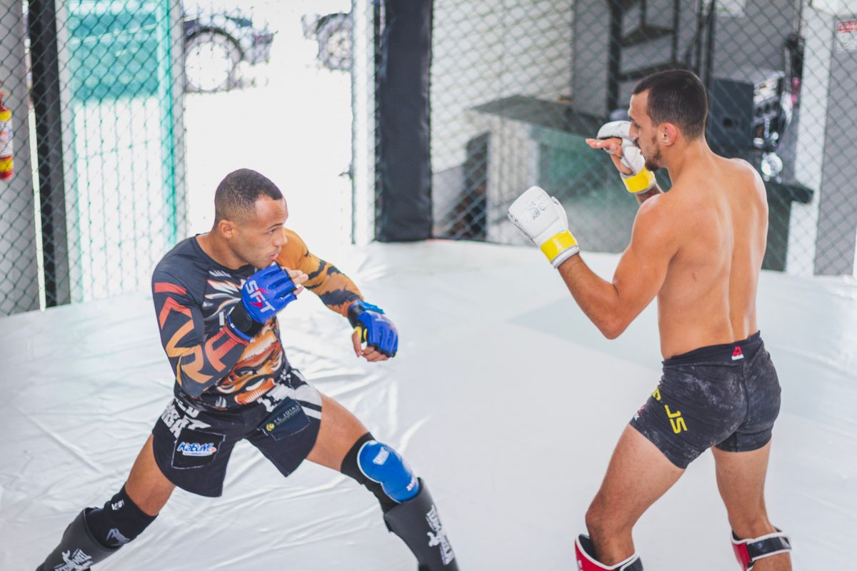 Two mixed martial artists sparring inside a cage