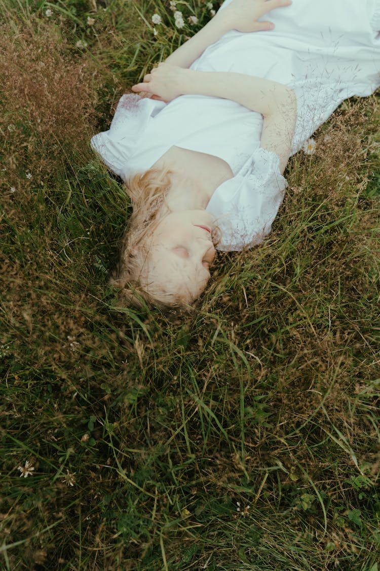 Woman In White Dress Lying On Green Grass