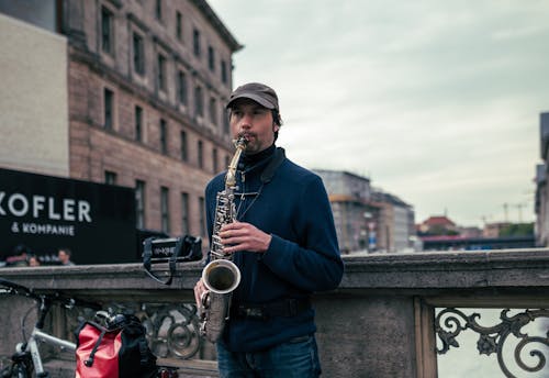 Man Playing Saxophone on a City Bridge