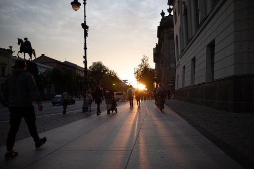 Free A vibrant urban street at sunset with people and cyclists casting long shadows. Stock Photo