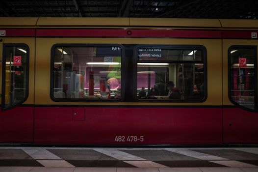 Passengers seen through a modern train window at an indoor station.