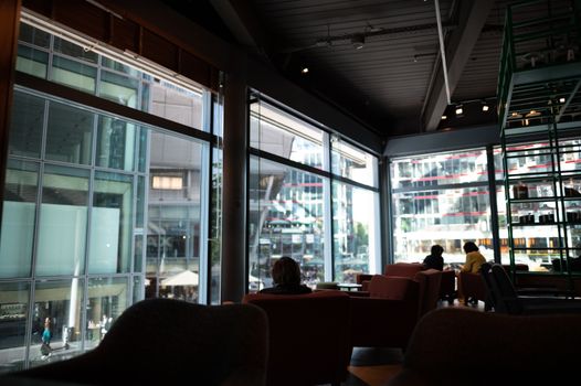 A contemporary cafe interior with large glass windows showcasing urban architecture outside.