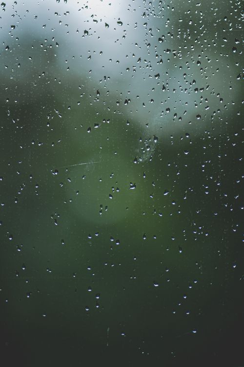 Free Close-up of raindrops on a window with blurred green nature background. Stock Photo