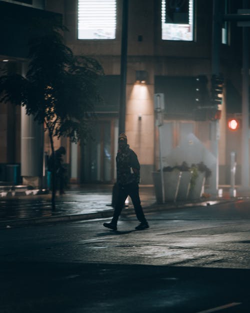 A Person with Mask Walking on Street during Night Time