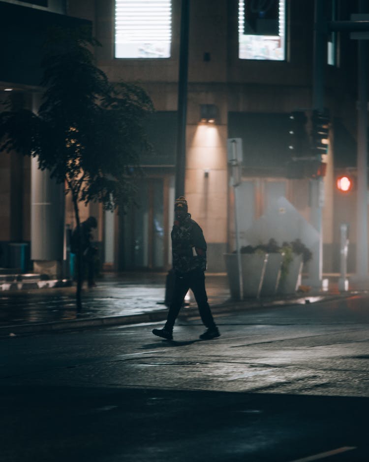 A Person With Mask Walking On Street During Night Time