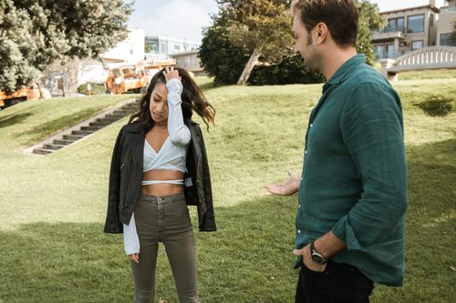 Free A man and woman engage in a casual conversation in a sunny park setting. Stock Photo