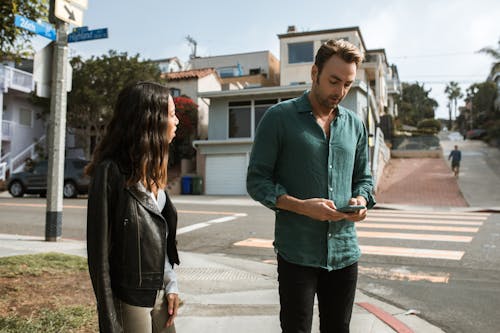 Мужчина в синей рубашке и женщина в черной куртке идут по тротуару