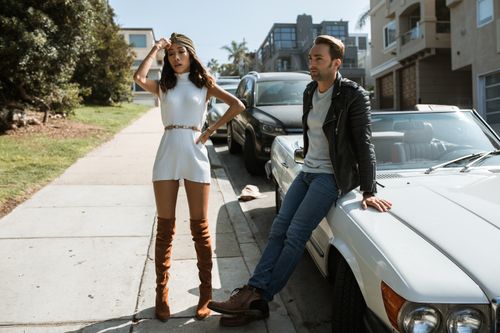 Free Fashionable couple in urban setting, posing by cars on a sunny street. Stock Photo