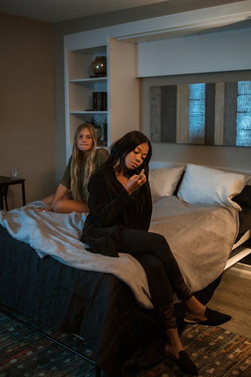 Two Women Sitting on Bed Having A Conversation