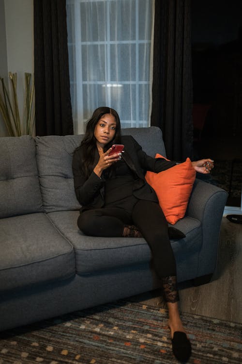 黑色長袖襯衫和黑色的褲子，坐在灰色的沙發上的女人